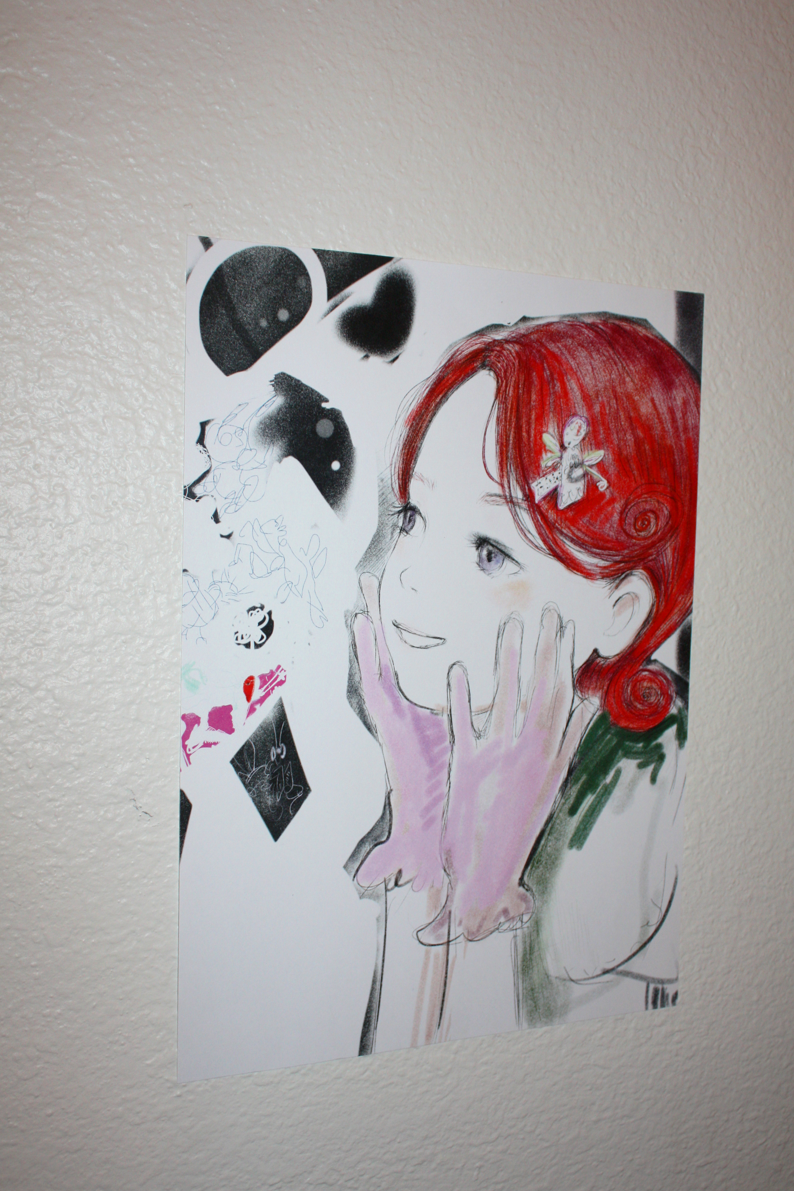 Detail of an anime girl with red hair hung on a white wall